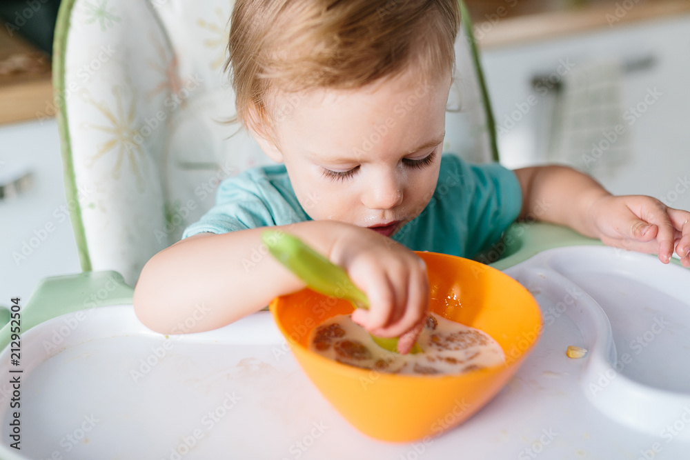 Portrait of adorable baby girl eating at home sitting at baby table . Portrait of adorable baby girl eating at home sitting at baby table .