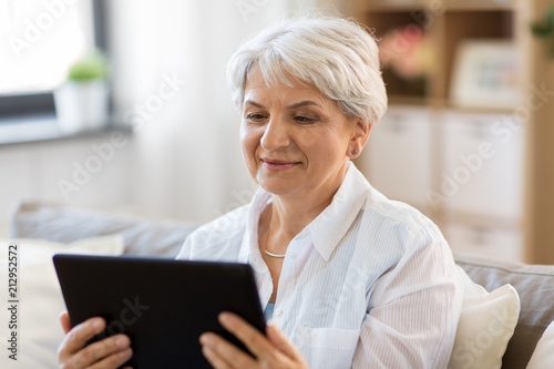 technology, age and people concept - happy senior woman with tablet pc computer at home