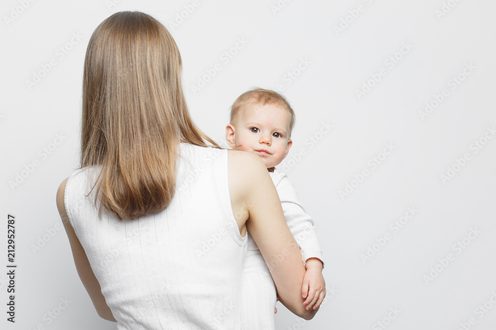 Young mother holding baby girl standing over white background. Young mother holding baby girl standing over white background.