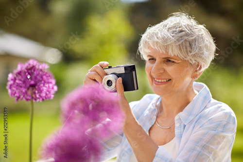 photography, leisure and people concept - happy senior woman with camera photographing flowers blooming at summer garden © Syda Productions