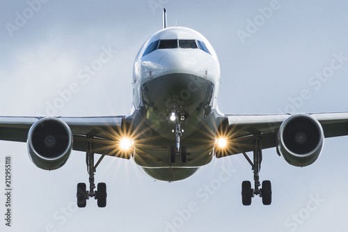Close-up on a white plane with landing lights about to land photo