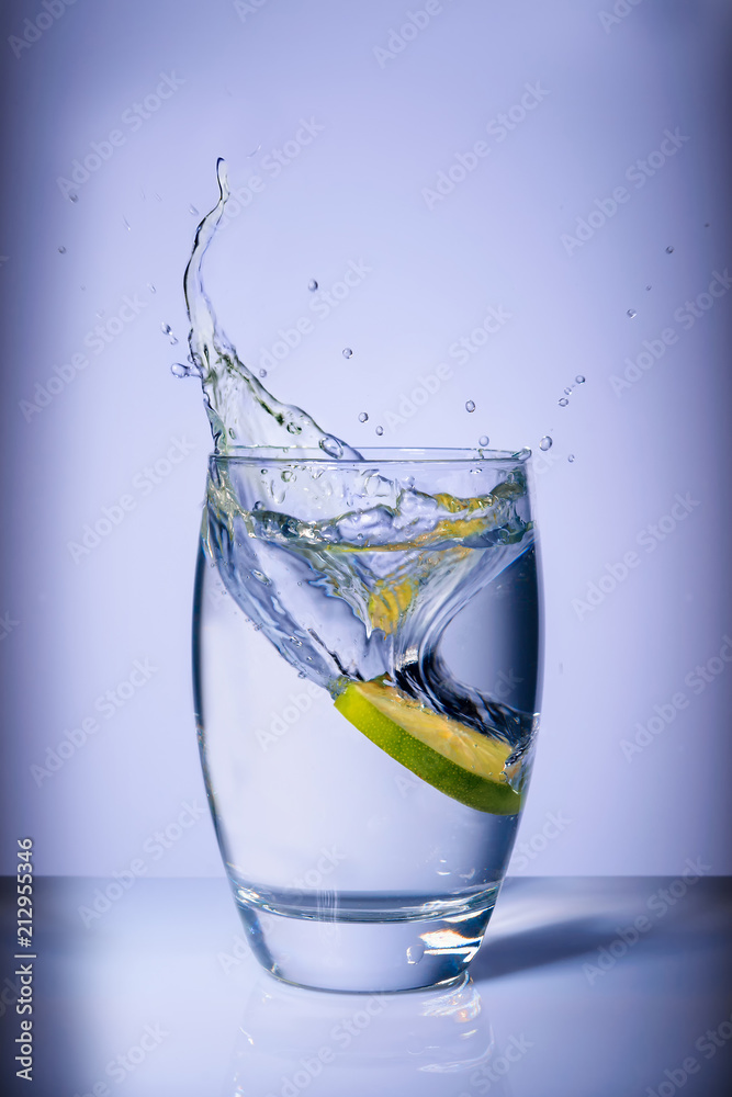 a slice of lemon drops into a glass of splash