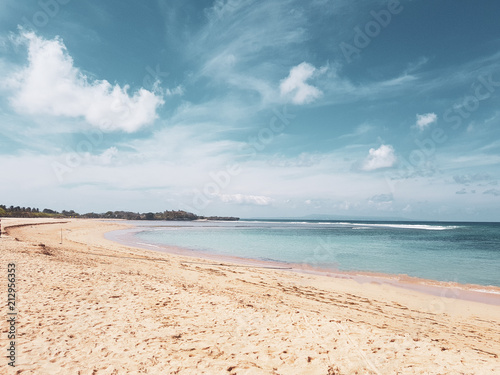 Beautiful empty sandy beach over beautiful ocean and summer cloudy sky background