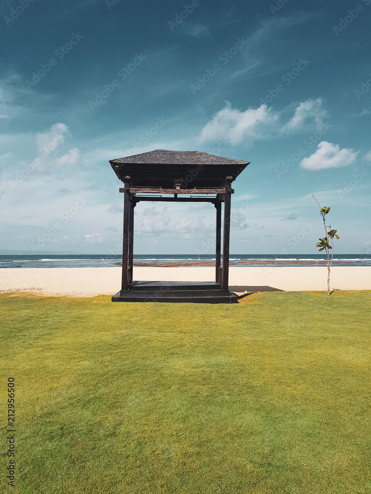 Wooden gazebo on the sandu beach against blue ocean and summer sky background Wooden gazebo on the sandu beach against blue ocean and summer sky background