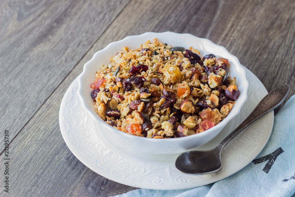 Homemade granola with oatmeal, dried fruits and nuts on a brown wooden table