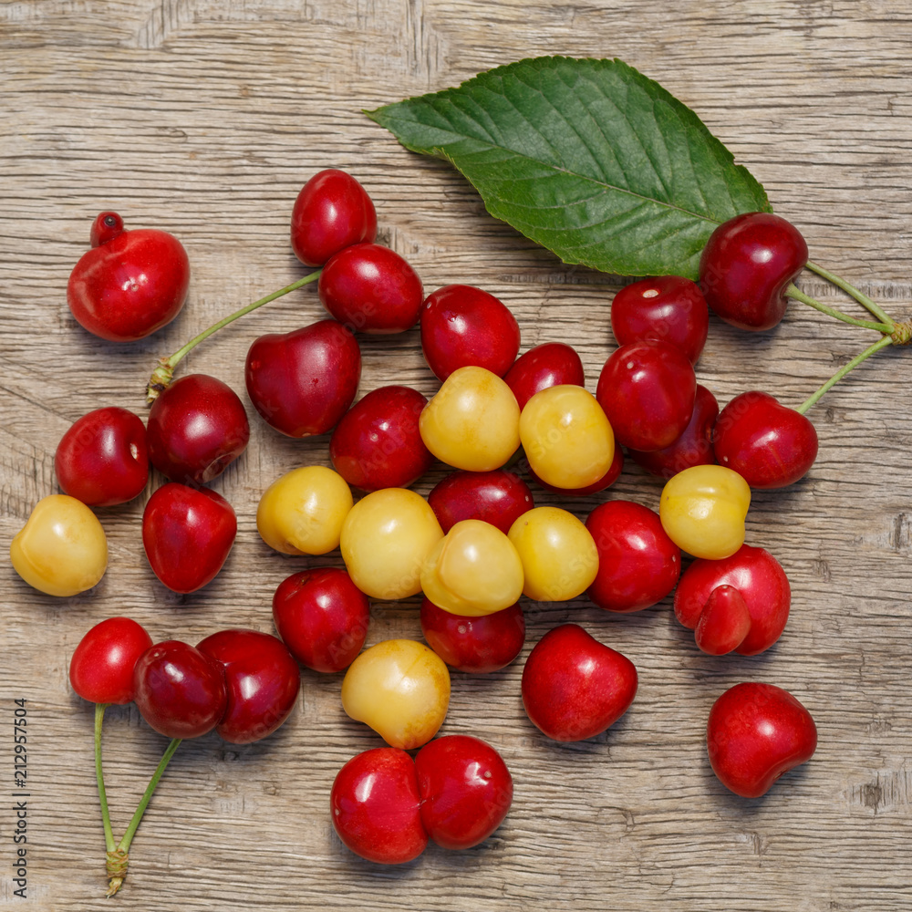 A lot of berries of red and white cherries are scattered over a old wooden surface of the table A lot of berries of red and white cherries are scattered over a old wooden surface of the table