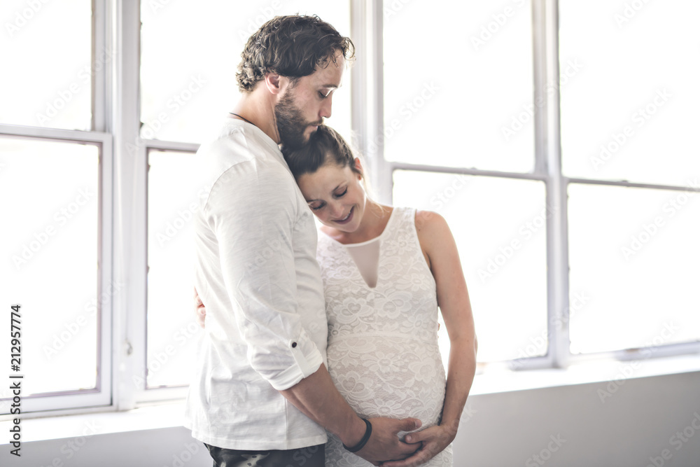 Handsome man and his beautiful pregnant wife standing near the window at home Handsome man and his beautiful pregnant wife standing near the window at home