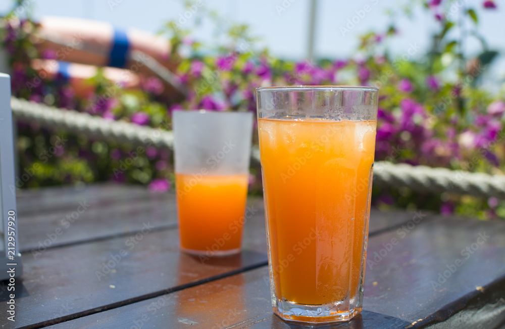 Two glasses with orange juice and ice on a wooden table