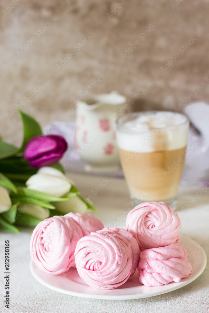 Pink homemade zephyr or marshmallow with cup of cappuccino coffee and flowers on light gray background. Marshmallow, Meringue, Zephyr Pink homemade zephyr or marshmallow with cup of cappuccino coffee and flowers on light gray background. Marshmallow, Meringue, Zephyr