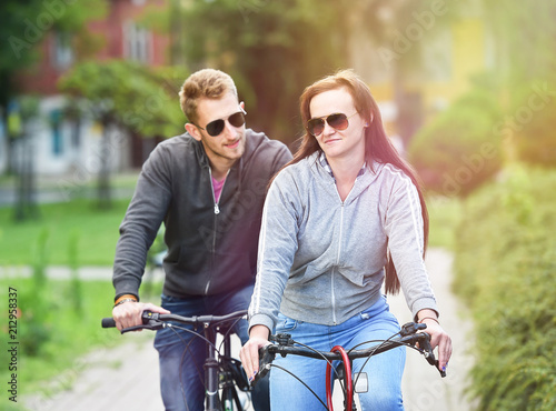 young couple riding bicycle together in a park