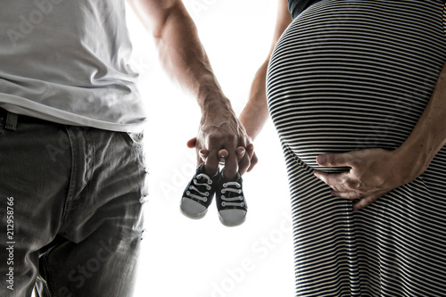 Pregnant woman and man holding baby shoes photo