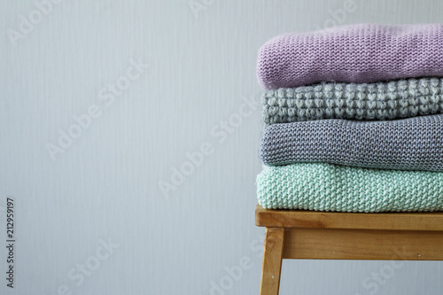 Stack of cozy knitted clothes on a wooden ladder. © lizaelesina