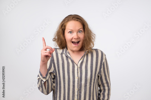 Photo of caucasian smiling lwoman isolated on white background pointing her finger in eureka sign photo