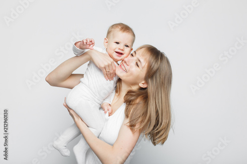 Happy beautiful young mother holding baby girl standing over white background .