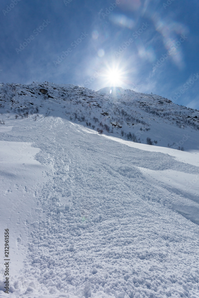 Sun lights falling on a snowed downhill  after avalanche.