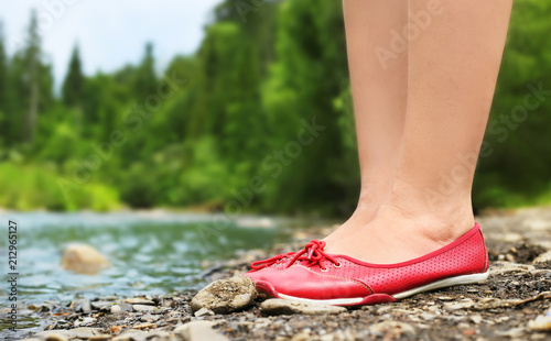 Female legs in red shoes on a background of landscape