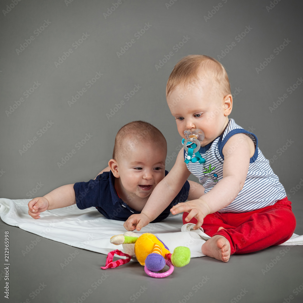 two infants playing with toy together two infants playing with toy together