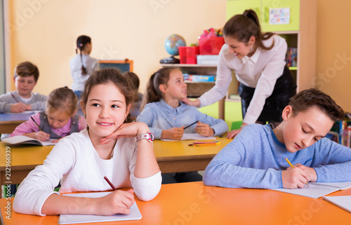 Portrait of young teacher woman at lesson with diligent school kids