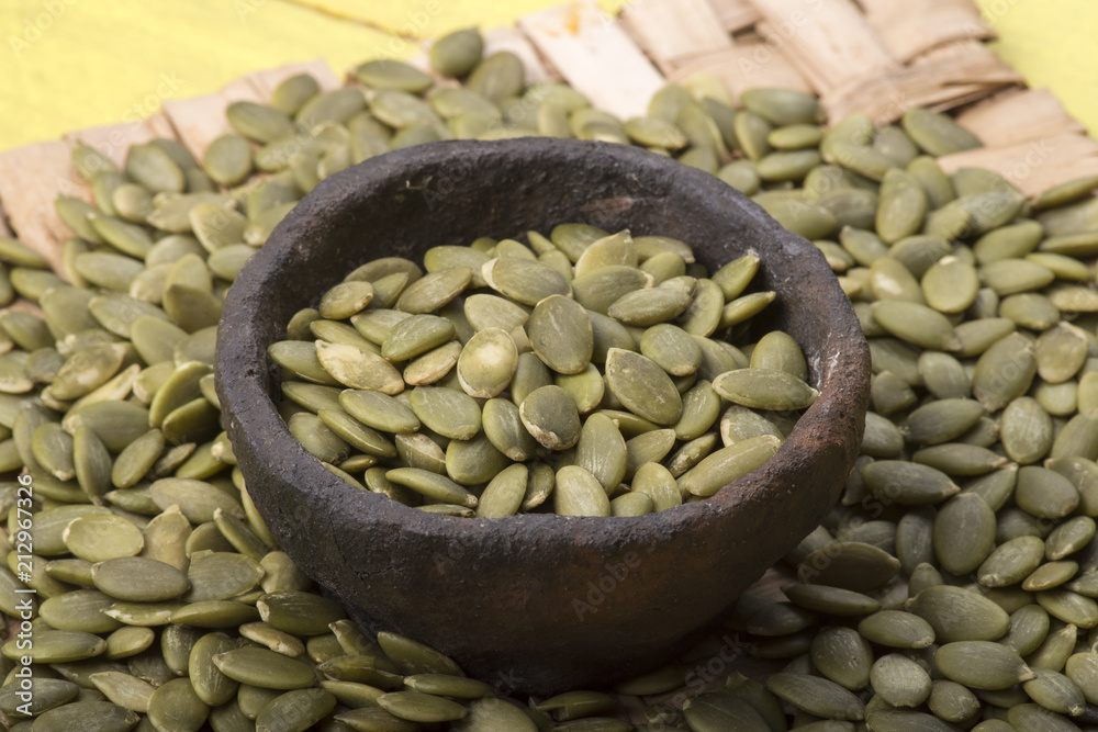 Naklejka premium Raw hulled pumpkin seeds in primtive bowl