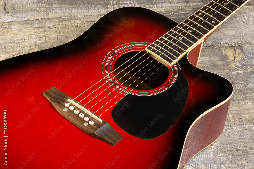 Fototapeta premium Guitar acoustic red, neck lying on a vintage background of wood on the background of old grunge boards. View sverkhplastichnost Spanish, of fingerboard and strings, the soundboard of the instrument