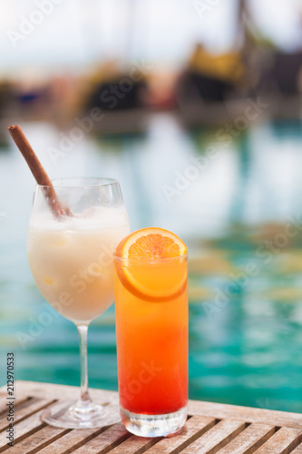 two perfect exotic cocktails on the table, pool background
