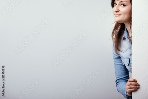 фотографія Cheeky young woman peering around a sign