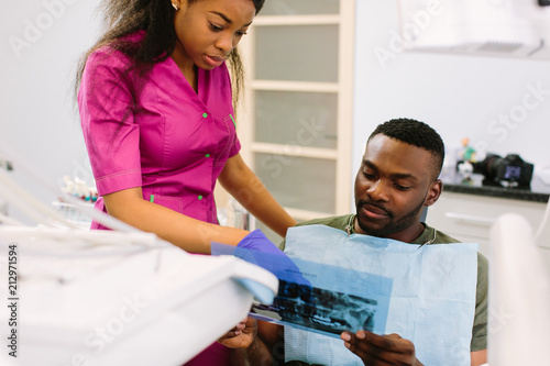 Female african dentist speaking with patient in dental clinic. photo