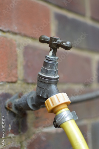 Steel tap with yellow hose pipe attached.