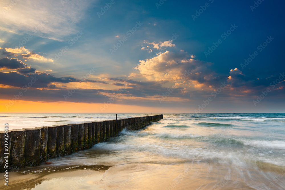 Obraz premium Sunset on the beach with breakwater, long time exposure