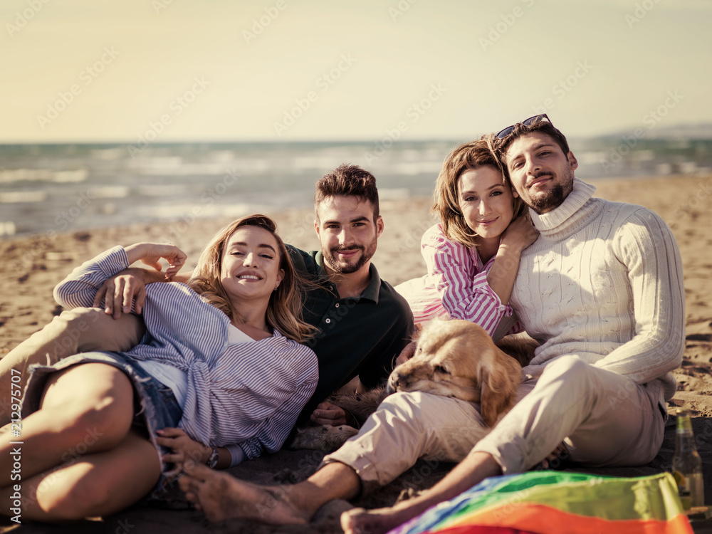 Group of friends having fun on beach during autumn day
