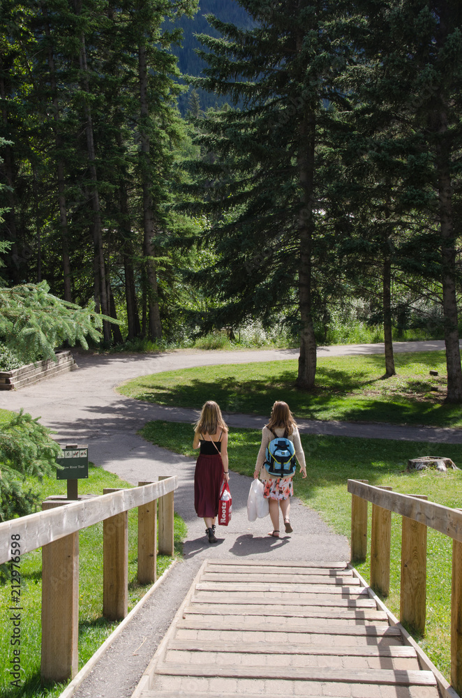 Two Young Girl Friends Walking in A Forest Park