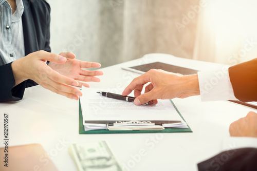 Businessman giving pen to business woman ready to sign contract making a deal , at meeting or negotiation.
