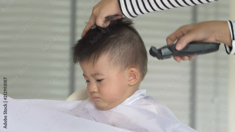 Baby boy cutting hair by his mom at home