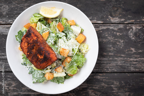 Flat lay of a blackened salmon Caesar salad on an old wood table