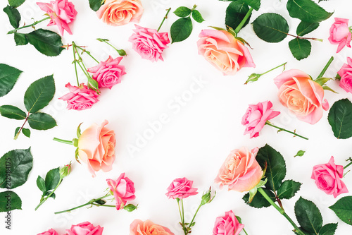 Floral round frame with roses flowers, petals and leaves on white background. Flat lay, top view.