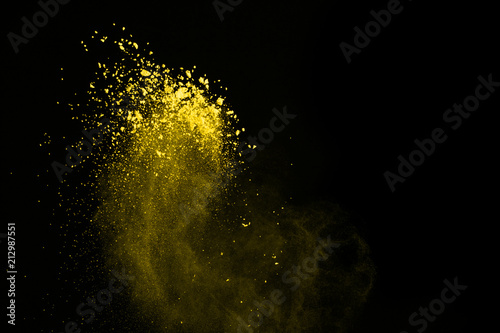 Abstract yellow dust explosion on black background. abstract yellow powder splatted on black background, Freeze motion of colored powder exploding.