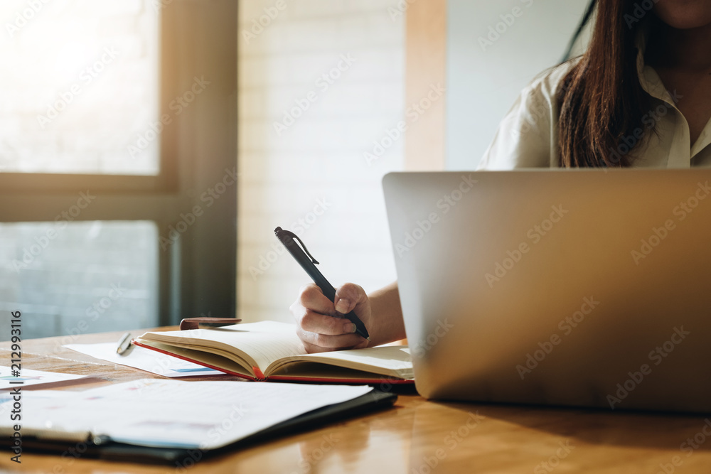 Business women using laptop computer and note some data on notepad - Business Financial Concept Business women using laptop computer and note some data on notepad - Business Financial Concept