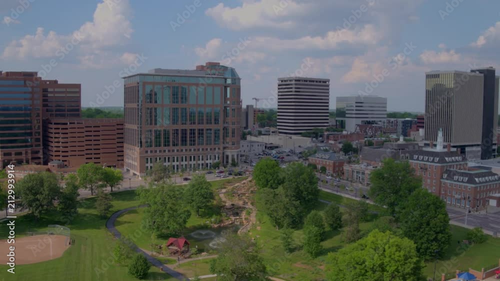 drone flying over Shaw Park in Clayton with swimming pool and baseball diamond. Camera pulls back along city buildings, clouds and blue sky. drone flying over Shaw Park in Clayton with swimming pool and baseball diamond. Camera pulls back along city buildings, clouds and blue sky.