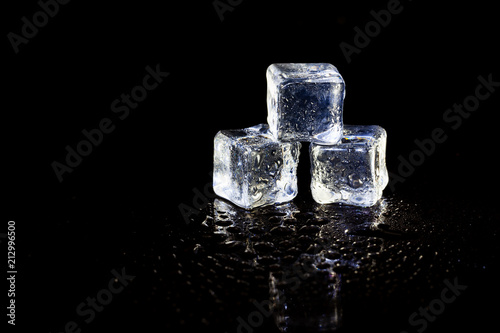 ice cubes reflection on black table background. © peterkai