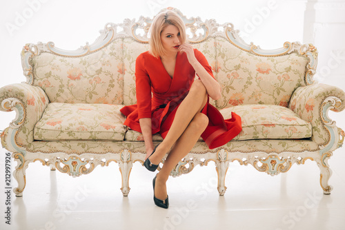fashion concept. shoe fashion and style of sexy woman. fashion model in red dress with slim legs. fashion look of sexy woman on sofa. confident businesswoman