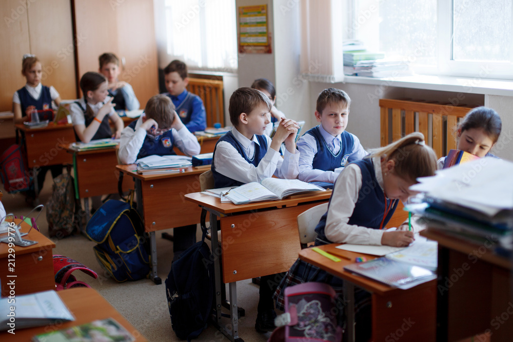 Pupils at the desk think and decide the task in the school. Primary education, training and people concept