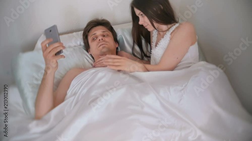 Husband refuses to have sex with his wife looking at his phone. She turns away and goes to bed.