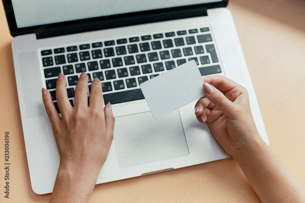 Close-up of woman holding credit card and using laptop Close-up of woman holding credit card and using laptop