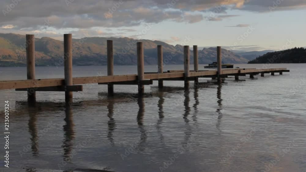 Calm Water Waves Rippling Beside Wooden Dock in Lake at Sunset Calm Water Waves Rippling Beside Wooden Dock in Lake at Sunset