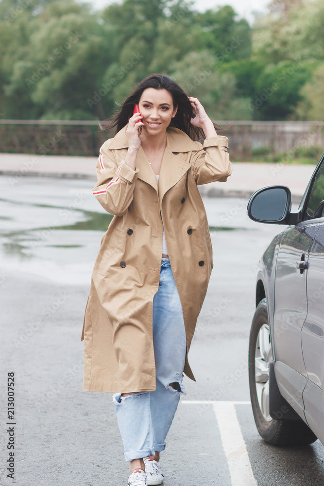 Beautiful woman in the beige coat and jeans on the street