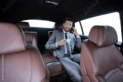 businessman sitting in car with cup and smartphone