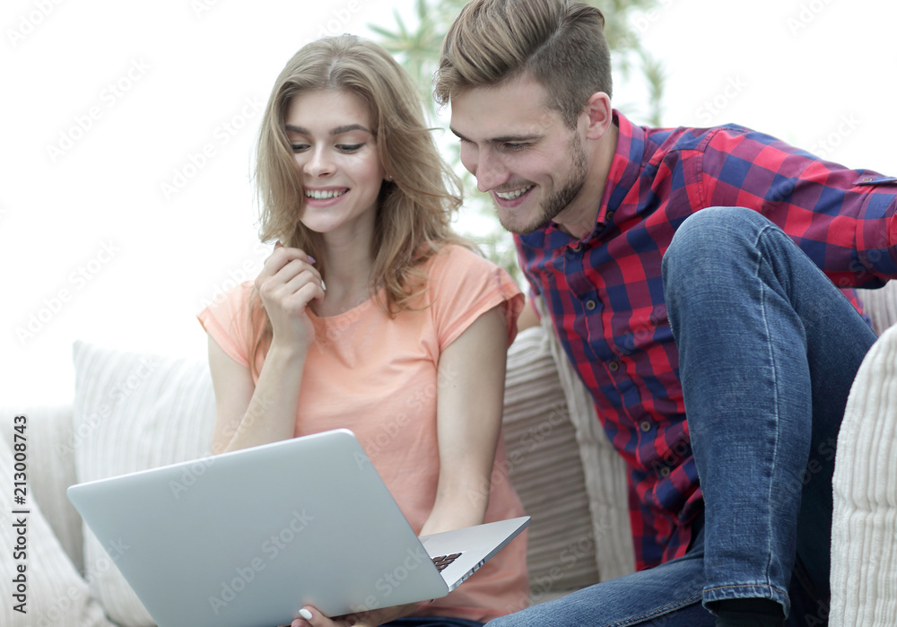 young man with his girlfriend watching a TV show on the laptop sitting in the living room young man with his girlfriend watching a TV show on the laptop sitting in the living room