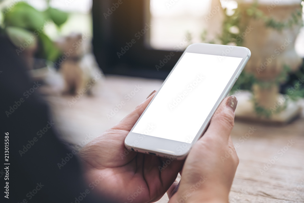 Mockup image of hand holding mobile phone with blank white screen in vintage cafe Mockup image of hand holding mobile phone with blank white screen in vintage cafe
