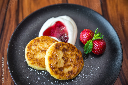 Cottage cheese pancakes. Russian syrniki with cranberry jam and yogurt, selective focus photo