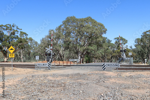 Fotografie a rural area train track level crossing with signs, lights and boom gates